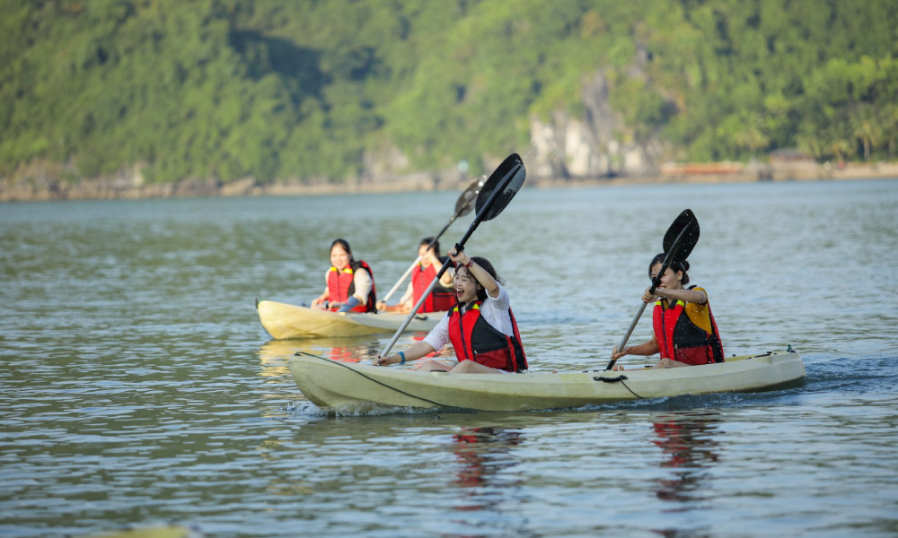 Two kayaks with four people wearing life jackets on the water.