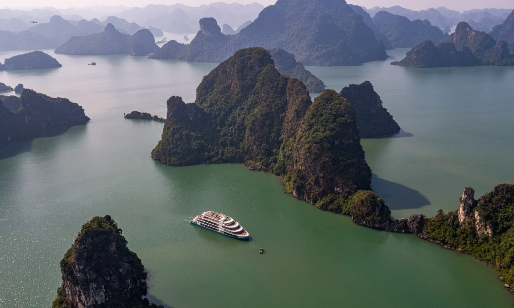 Panoramic view of Halong Bay islands with the Capella Cruise in the middle captured by flycam.