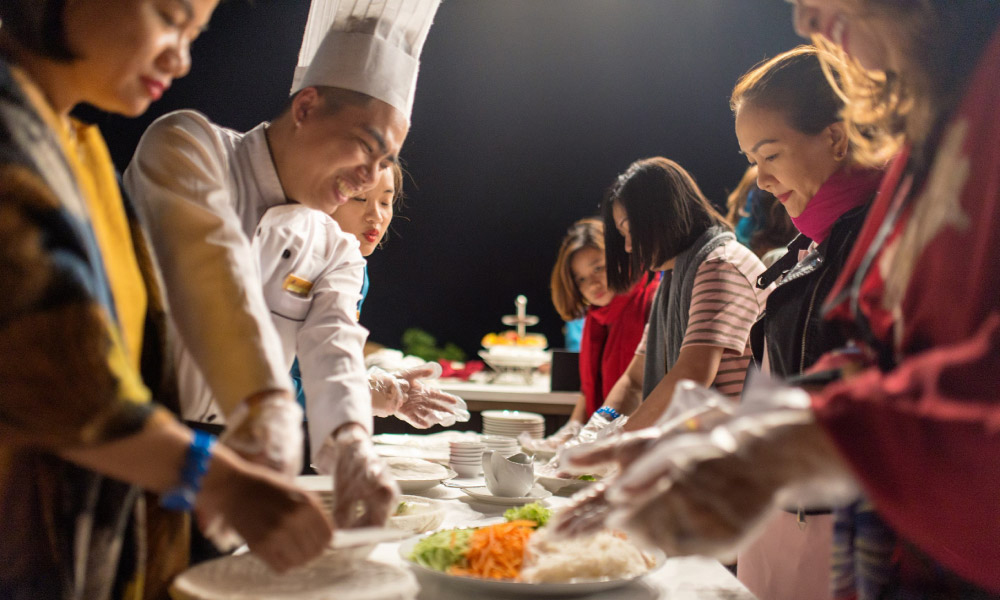 Guests of Capella cruise and a chef making pho cuon.