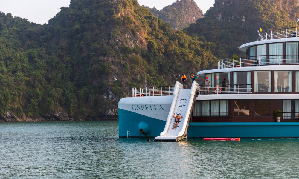 A corner of Capella Cruise in front of an island, with a person sliding down a water slide.