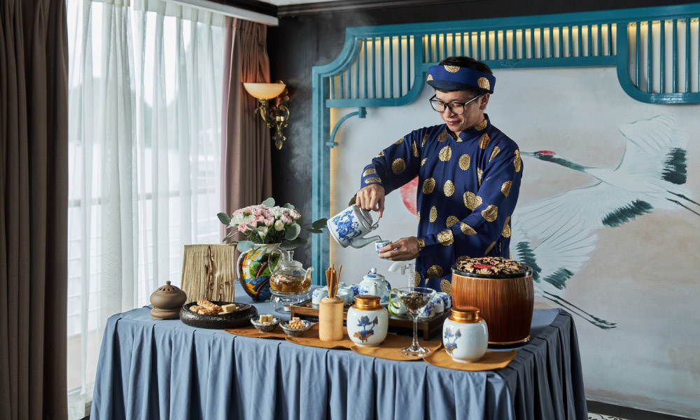 A staff of Capella cruise in traditional vietnamese clothing making tea.