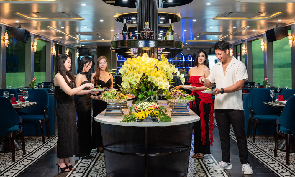 Guests standing around the buffet station in the middle of a restaurant with sea-view windows.