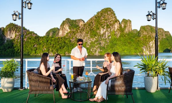 Five people talking on lounge chairs on a cruise with Halong islands behind.
