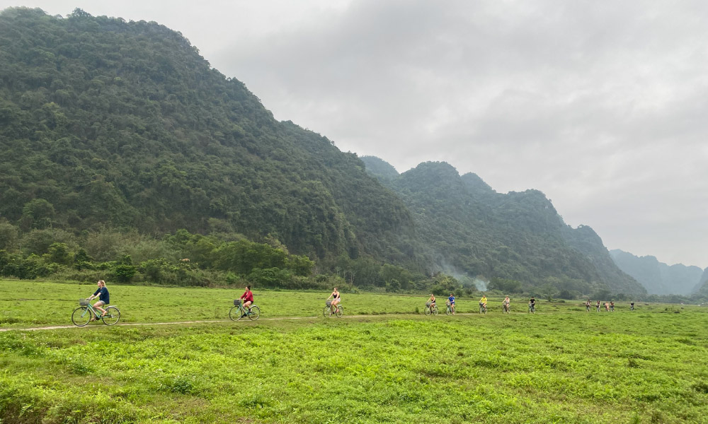 Biking ride on Cat Ba Island with mountains behind.