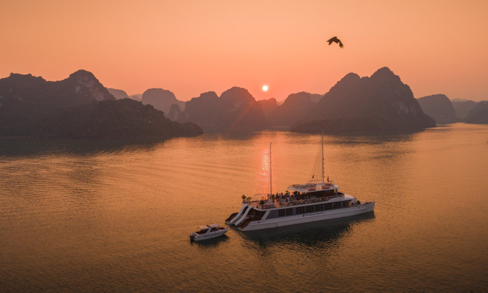 Halong sunset view with Cat Ba Catamaran cruise passing the islands.