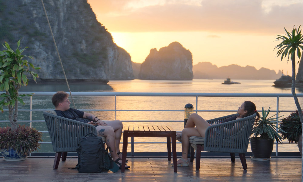 Guests sitting on a chairs looking out to Halong Bay during the evening.