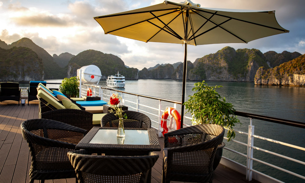 a table and umbrella on a deck looking out to halong bay