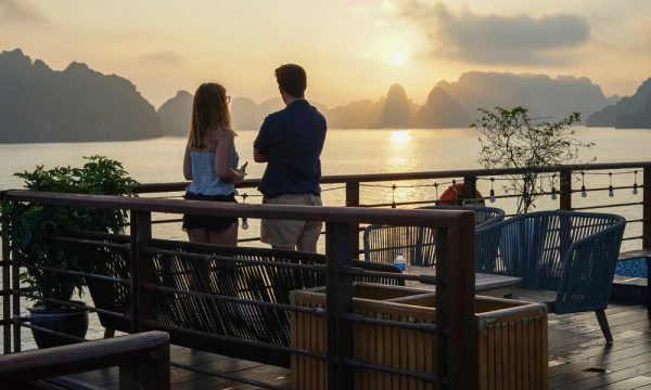 a couple standing on the deck of peony cruise admiring halong sunset