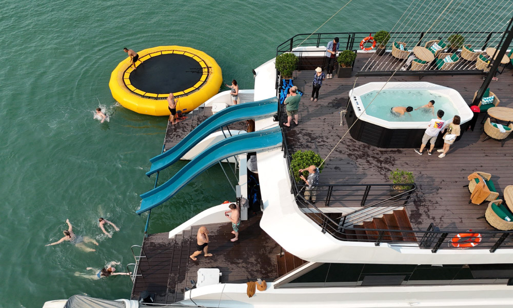 The top deck with jacuzzi, water slides, and trampoline of Halong Catamaran looking from above.