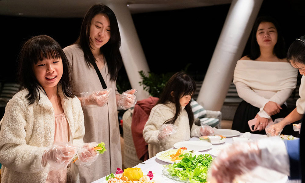 four people making spring rolls