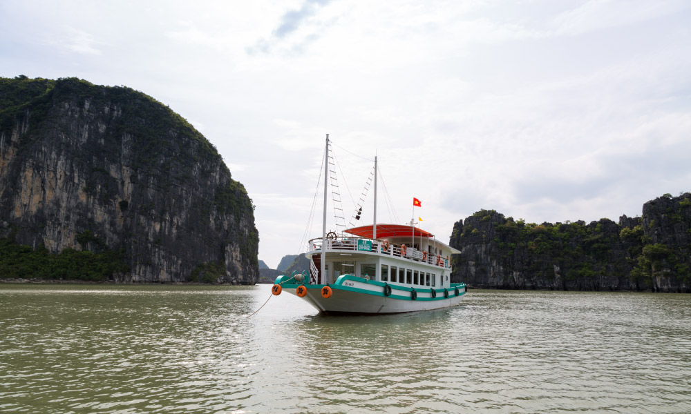 A small boat cruising through Halong Bay islands.