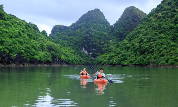 Two kayaks sailing in front of fgreen mountains on Halong islands.