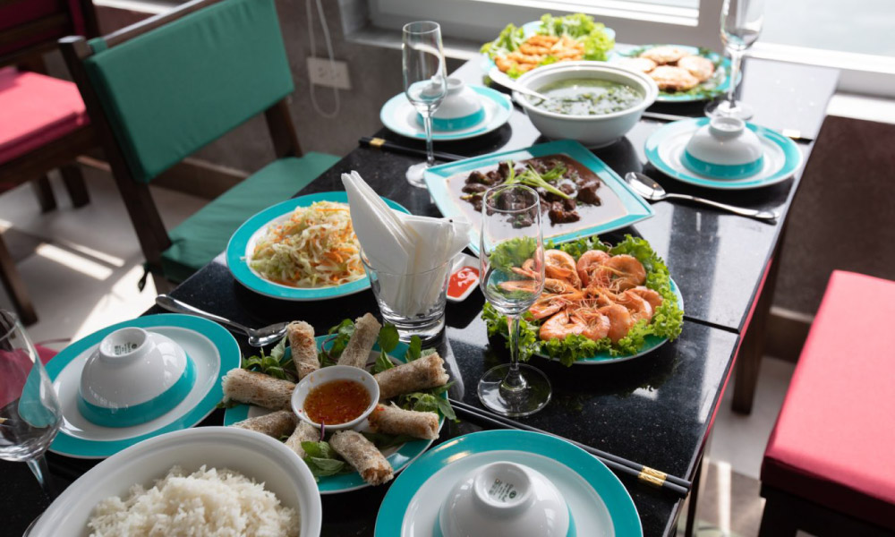 A table with many dishes on turquoise round plates.