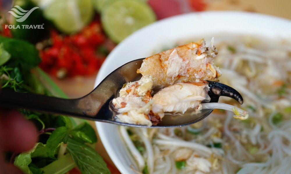 A bowl of noodles with a spoon holding some seafood.