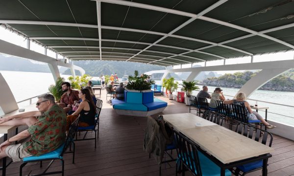 A sundeck with ceiling and lounge chairs looking out to Halong Bay islands.