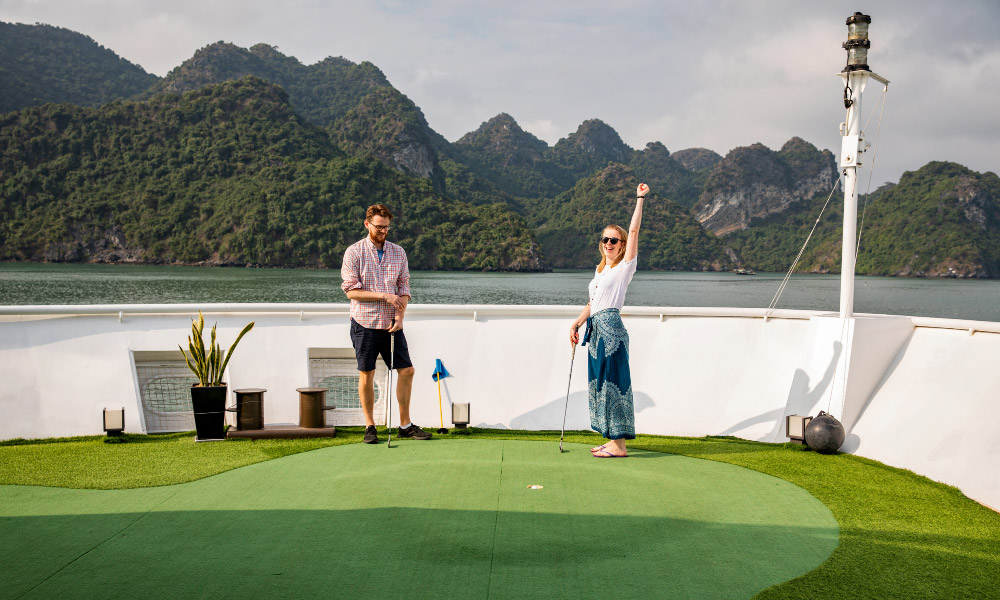 two people playing golf on the couse with halong bay islands behind them