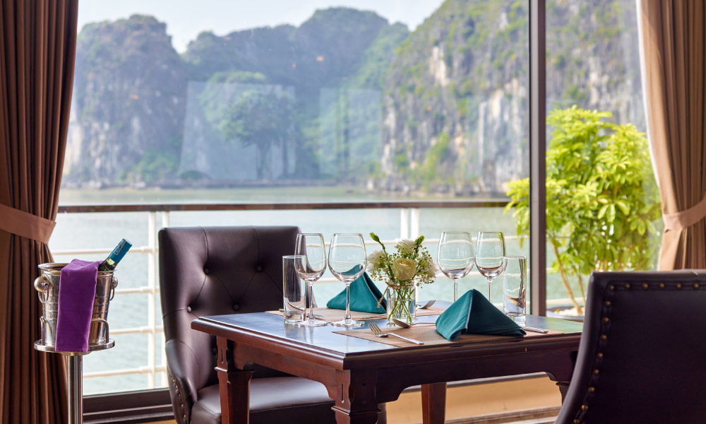 view of halong bay islands looking through the glass window of the restaurant with a table in front of it