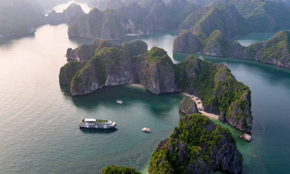 drone photo of halong islands with the mon cheri cruise in the middle