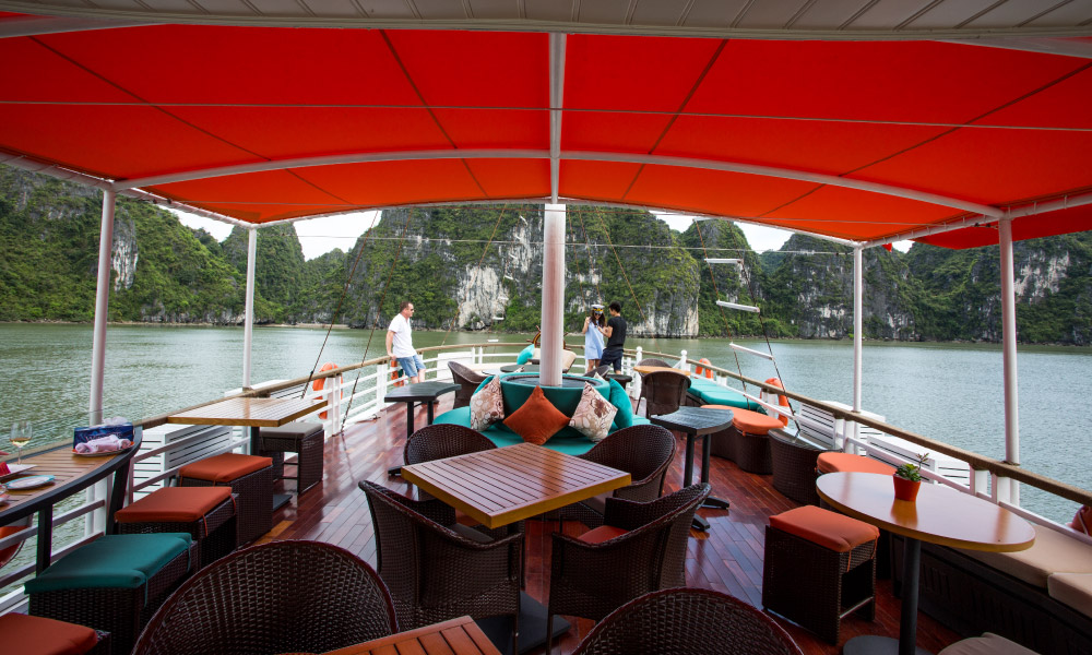 The sundeck with many tables and view of Halong Bay outside.