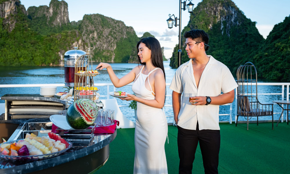 A couple standing on a sundeck, taking drinks and snacks.