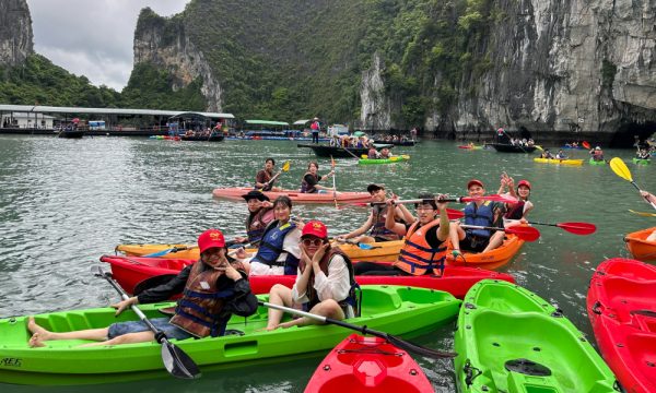 Halong visitors on green and red kayaks gathering before going through a cave.