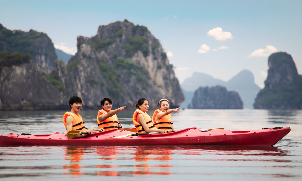 two kayaks with four people in the middle of halong islands