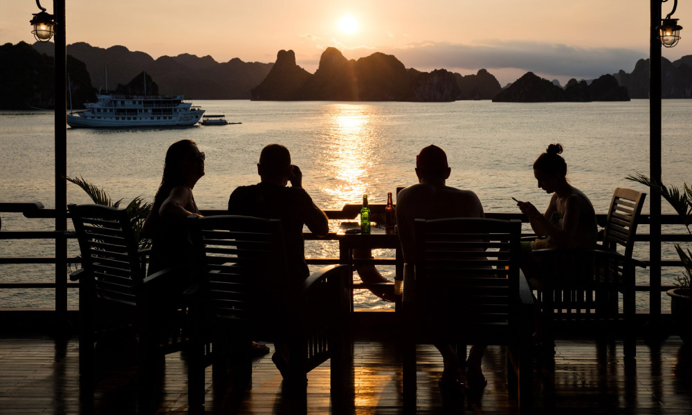 four people sitting on the sundeck watching halong sunset