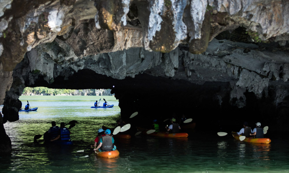 a group of kayaks cruising through luon cave