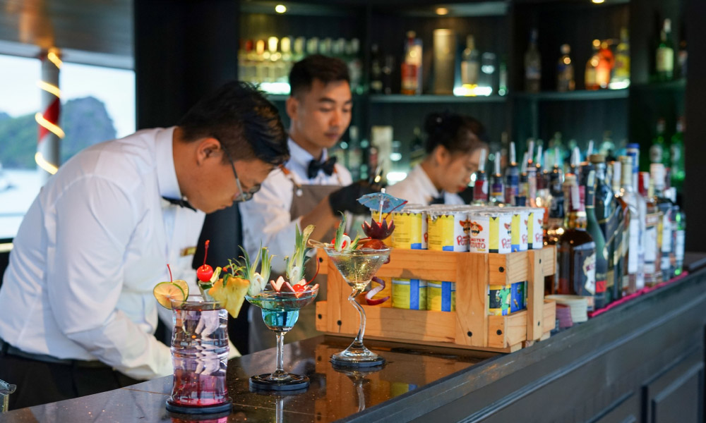 a bartender making drinks as another stand beside him