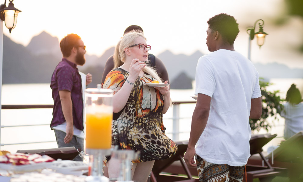 guests talking on a sundeck with halong islands in the background