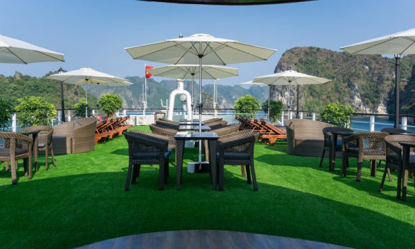 the sundeck on mon cheri cruises with groups of tables and umbrellas and fake grass floor