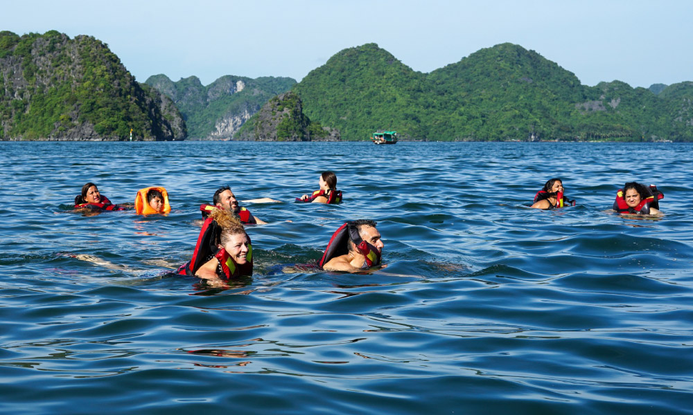 guests of mon cheri cruise swimming in the blue water of halong bay