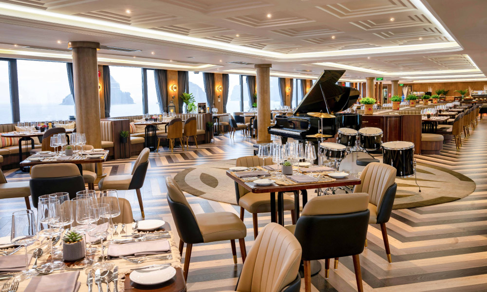 A restaurant with luxury tables, big windows and a piano.