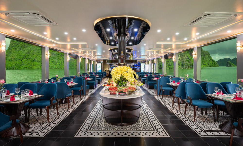 Overview of a restaurant with bluw chairs on the side, below big windows, and a buffet station in the middle.