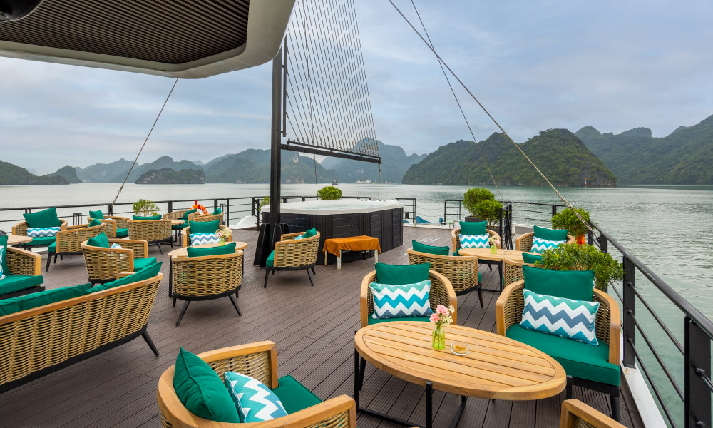 Overview of the sundeck on Halong Catamaran Cruise with tables and lounge chairs, and a big jacuzzi in the middle.