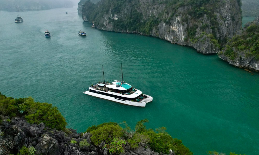 The Halong Catamaran Premium Cruise sailing in the middle of two islands.