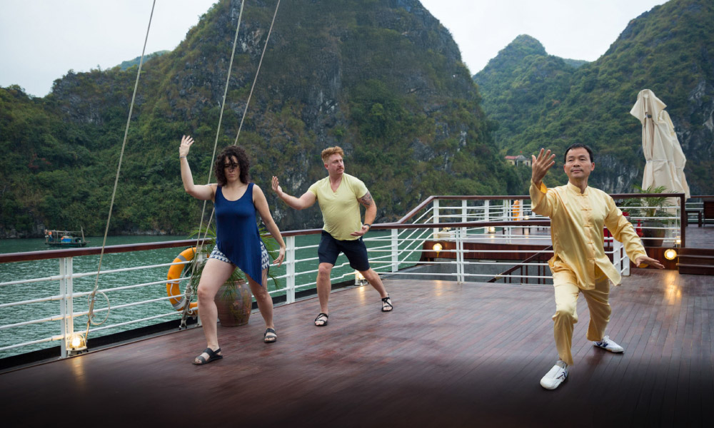 three people practice tai chi on the sundeck of peony cruise