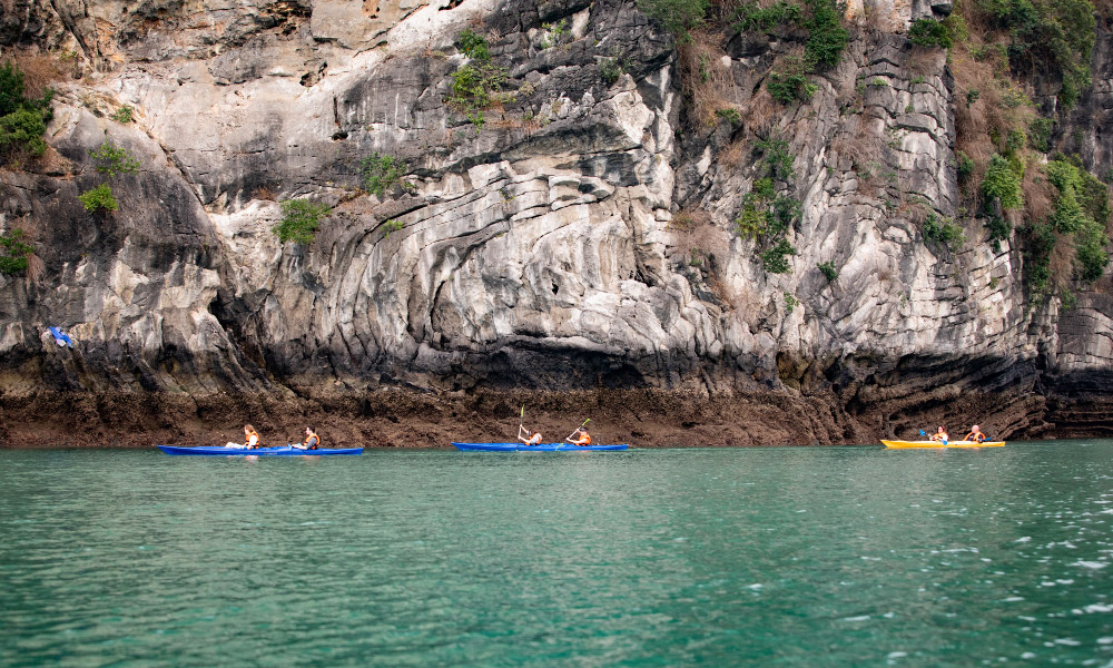 a few kayaks going under a big island