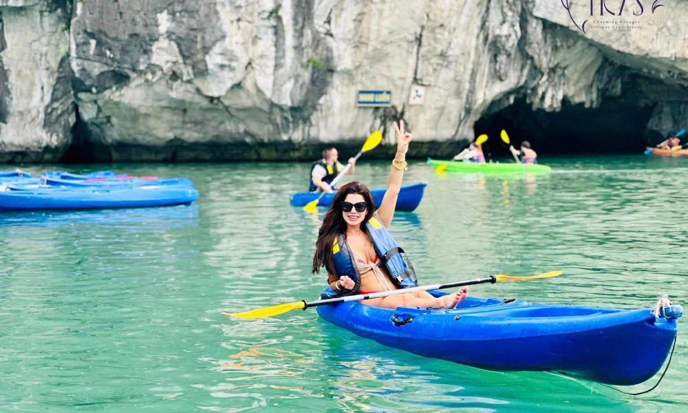 Several blue kayaks going out of Luon Cave in Halong Bay.