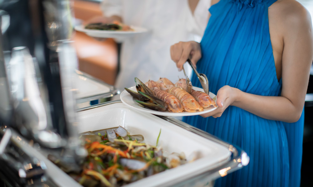 a person getting shrimps from a buffet tray