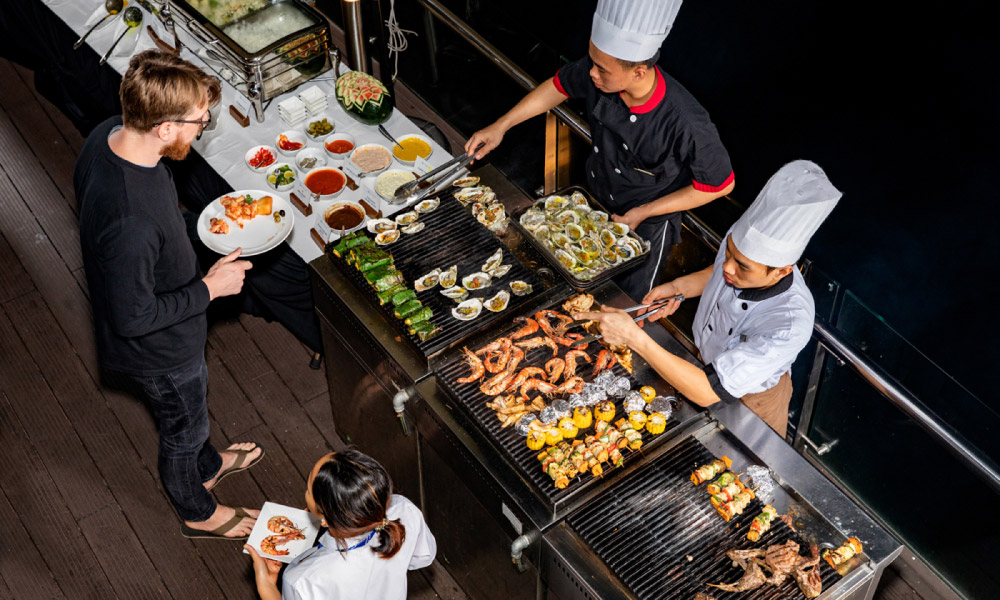 a bbq station with two chefs cooking and guests taking food