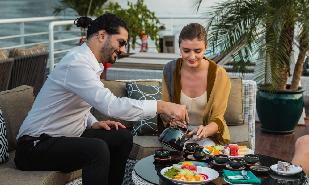 A couple enjoy tea party on a cruise deck.