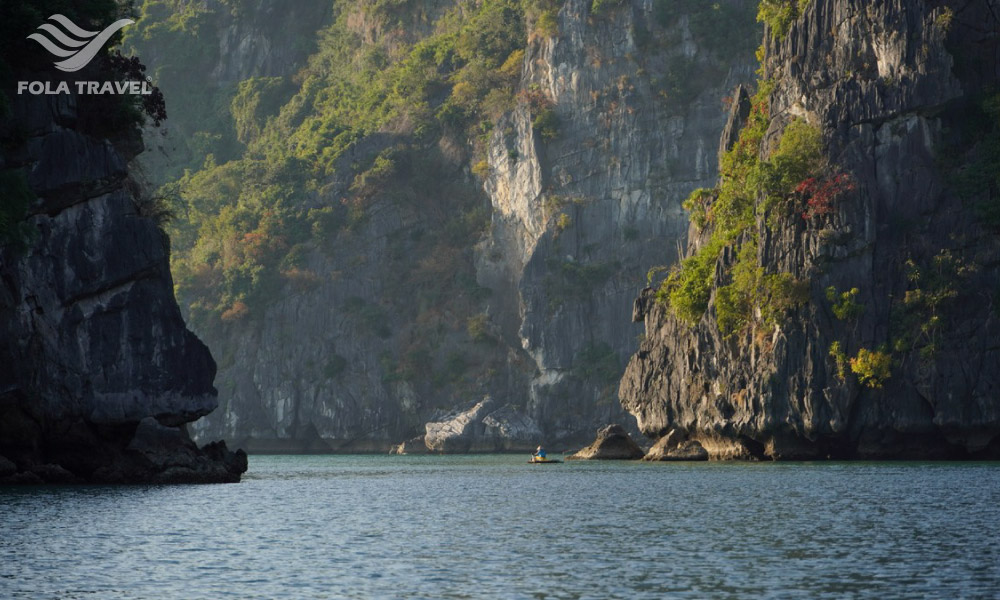 Bai Tu Long Bay islands and sea with a small boat and fishermen going between the islands.