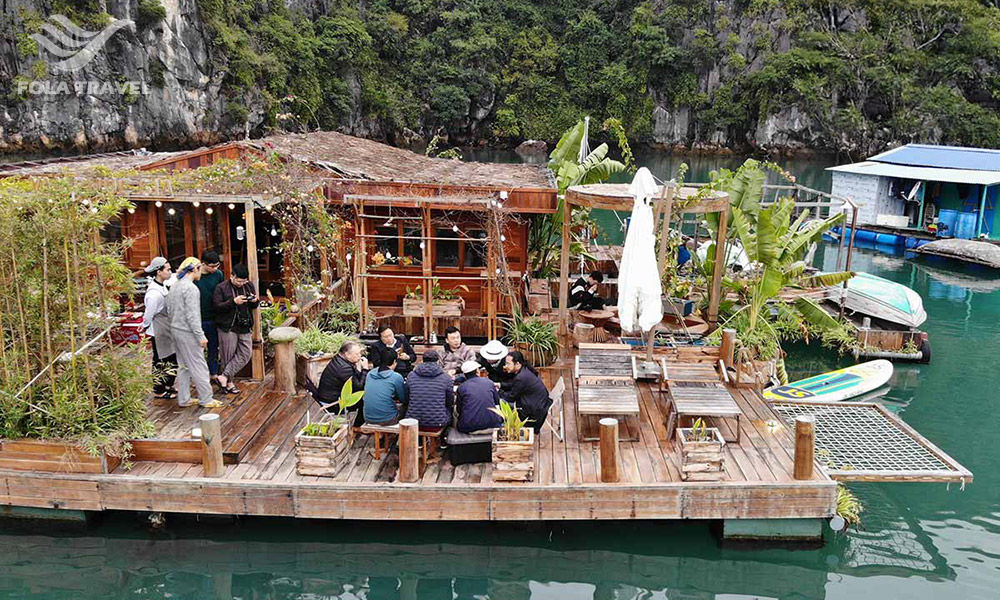 The floating homestay on the water with guests sitting in the front.