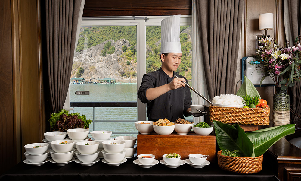 A chef making noodles in front of a window.