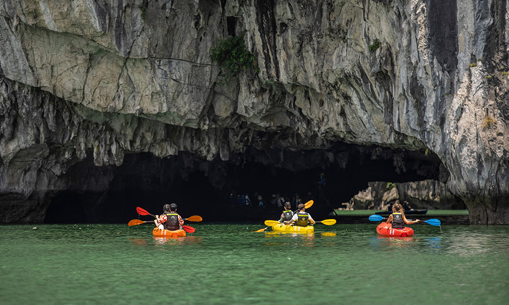 Many people on colorful kayak prepare to go through Luon Cave.