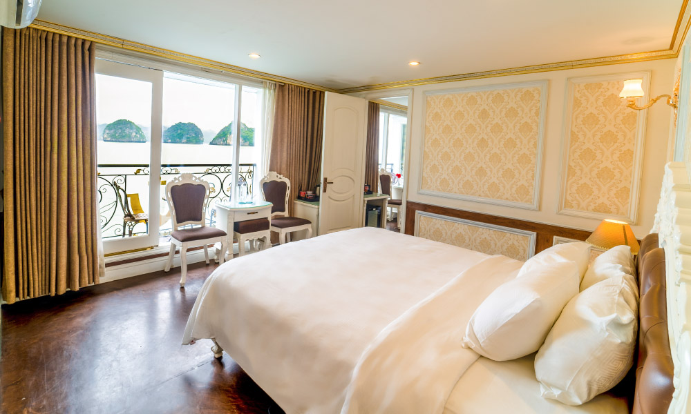 Room with close up of a bed facing the window and balcony, with yellow accent wall and a door on the right.