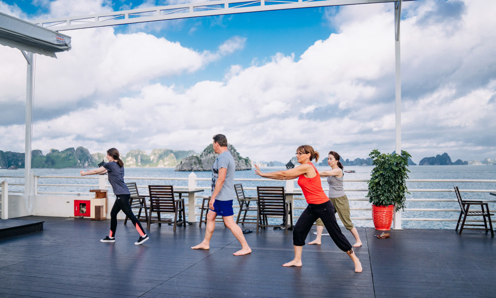 Four people doing tai chi on the deck of a cruise.