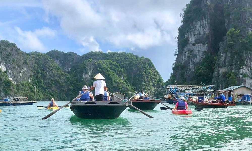 Halong visitors on bamboo boats and kayaks on the water.