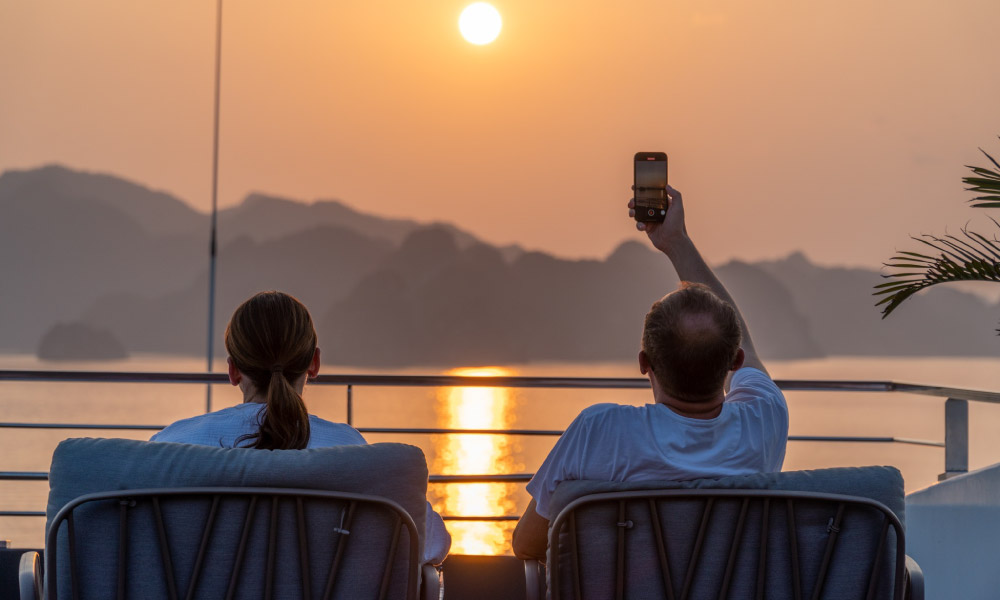 guests take picture with sunset view of halong bay